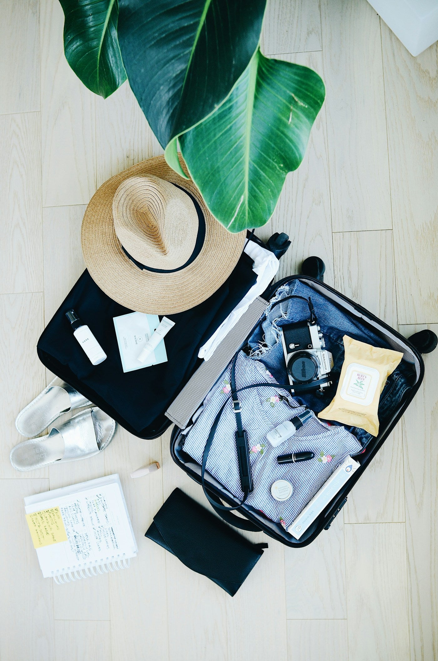 Travel inspiration: an open suitcase, straw hat and clothing laid out before a trip